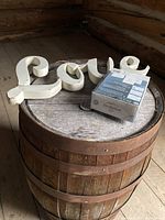 White metal 'love' sign and boxed invitation kit on round wooden barrel.