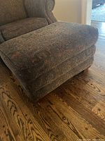 Photo of whole ottoman showing its shape, size in context with nearby furniture, and fabric pattern.