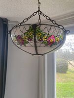 Photo of one stained glass hanging light fixture showing floral design and metal hanging chain