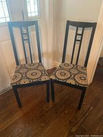 Two painted wood dining chairs side-by-side showing front and seat cushion details.