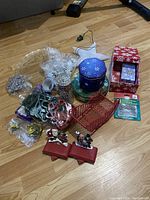 Overview of Christmas lot showing tins, decorative boxes, bead strands, stocking holders, and ornament hangers.