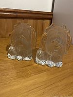 Front view of the two frosted glass Yorkie dog puppy bookends placed side by side on a wooden surface, showing detailed dog faces and clear glass bases.