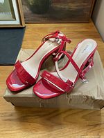 Front and top angled view of the pair of red patent leather ladies shoes showing open toe and straps.