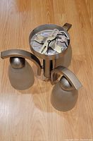 3-light brushed chrome ceiling fixture with frosted glass shades seen from top showing wiring and metal structure.