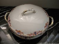 Top view of round Limoges covered dish showing art-deco border design, gold handles and rim.