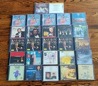 Photo showing 25 classical music CDs arranged on wooden surface with visible artwork featuring Karajan Festival, Pavarotti, Mozart, Berlioz, Liszt, Gershwin, and others