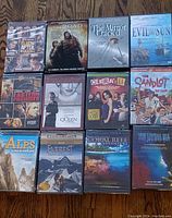 Photo showing front covers of 14 DVDs in the lot arranged on wooden floor, titles visible.