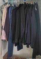 Various jackets and a pair of jeans hanging on closet rod