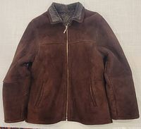 Front view of brown microsuede jacket with full zipper and two front zippered pockets, showing structured collar with grey sherpa lining visible at the collar edge.