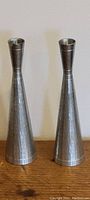 Front view of two matching vintage Selangor pewter bud vases with hammered texture and matte silver color, standing side by side on wood surface.