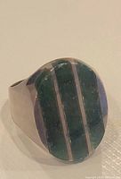 Front view of the sterling silver men's ring showing the oval-shaped top with three vertical green stone inlays separated by silver strips.