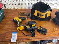 All items shown on wooden table: Dewalt cordless drill, two batteries, charger, various drill bits, and Dewalt zippered carry bag.