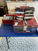 Sony DVR 4000 dual deck DVD + VCR player box with assorted DVDs and VHS tapes stacked above