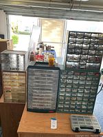 Overview of five plastic hardware organizers of different sizes with contents visible through transparent drawers and compartments