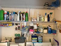 Image showing shelves in laundry closet with a variety of cleaning sprays, bottles, gloves, cloths, and cleaning accessories organized neatly.