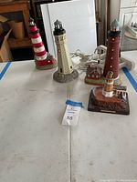 Four decorative lighthouse figurines arranged on a table, showing overall lot contents.