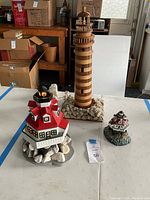Photo shows all three lighthouses on table, with surrounding garage background and boxes