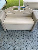 Front view of beige Rubbermaid outdoor storage bench showing hinged top for storage.