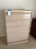 Front view of the tall dresser showing five spacious drawers with horizontal groove handles.