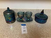 Photo of vintage Indiana Glass iridescent carnival glass set with grape design including two candy dishes with lids, a sugar and creamer set, and a tray