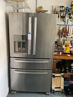 Front view of stainless steel Whirlpool French door refrigerator showing water and ice dispenser and bottom drawers