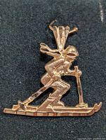Close-up of 10K gold skier pendant showing detailed figure and skiing posture.