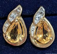 Front view showing pear-shaped citrine gemstones surrounded by diamond accents in 10K gold earrings.