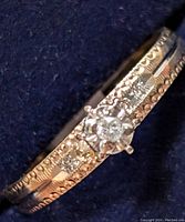 Close-up image of the detailed gold band and diamond centerpiece showing texture and diamond arrangement.