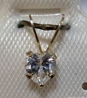 Close-up of heart-shaped clear cubic zirconia set in 14K gold pendant with a V-shaped bail.
