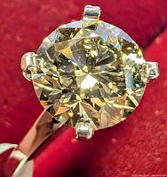 Close-up of round brilliant cut diamond showing yellow hue and clarity.