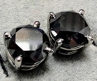 Close-up front view of pair of round black diamonds in four-prong 14K white gold settings