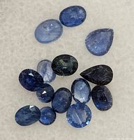 Close-up of loose blue sapphires on a white surface showing varied hues and cuts
