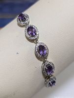 Close-up of the silver bracelet showing oval amethyst stones surrounded by cubic zirconia and the polished chain.