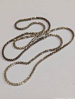 Full view of the silver chain necklace laid flat on a white background showing length and shiny facets.
