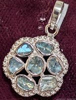 Front view of antique silver pendant with seven irregular blue-green stones and diamond halo