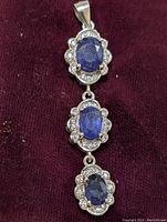 Full length view of silver pendant with three linked oval sapphires and CZ accents