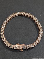 Overview of the bracelet laid flat on black background showing the continuous line of morganite stones and clasp.