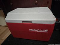 Closed view of the Coleman Poly Lite 40 cooler showing red body and white lid with logo.