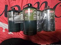 Photo showing six Coleman propane canisters, focusing on labels and packaging.