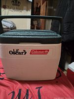 Front view of Lil Oscar Coleman cooler showing brand logos on white body with dark green lid