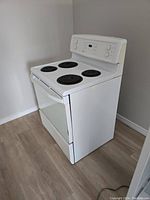Angled view of white freestanding electric stove with four coil burners
