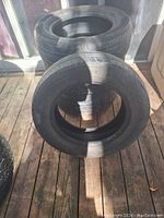 Two black tires stacked on a wooden floor, showing overall condition of the tires.