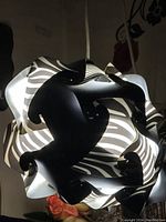 Top down view of uniquely shaped black and white lamp with interlocking curved pieces forming a sphere.