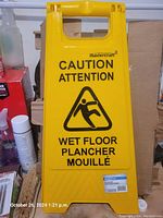 Photo of one yellow Mastercraft wet floor caution sign showing bilingual warning text and slipping figure symbol.
