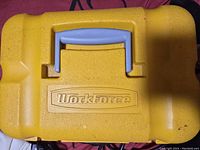 Closed yellow WorkForce carrying case for tile saw with molded handle.