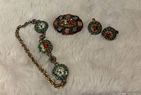 Full view of the set showing bracelet, brooch, and earrings on light surface