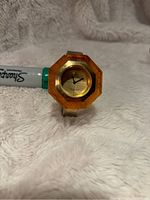 Close-up front view of the watch showing the octagonal amber-colored bakelite case and gold-tone dial with simple black hands.