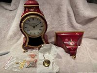 Front view of the mantel clock and matching wall shelf with floral decorations on a soft surface.