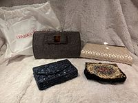 The lot showing all four evening bags displayed on a light-colored plush background, including the Ivanka Trump bag's dust cover.