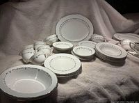 Wide angle shot showing the full set of Foley Silver Chantilly china including cups, plates, serving bowls, and platters arranged on a soft beige fabric.